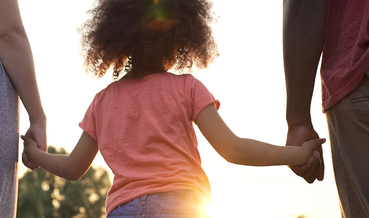 Child holding hands with parents